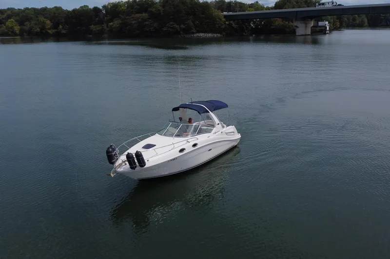 Slide: The Image of 2006 Sea Ray 260 Sundancer boat on calm water near a bridge. - 9
