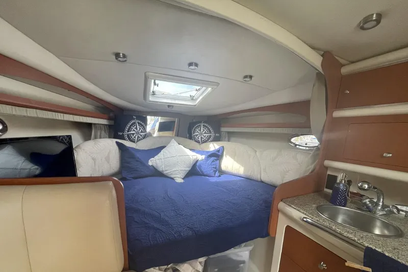 Slide: The Image of 2005 Chaparral 290 Signature cabin interior with bed, sink, and nautical decor. - 5