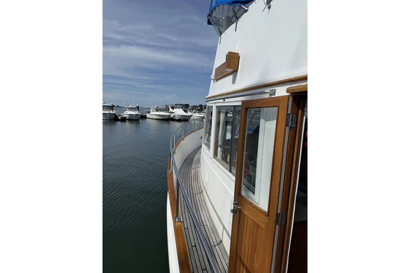 Slide: The Image of 1999 Grand Banks 42 Classic yacht docked at marina, showcasing wooden deck and cabin. - 12