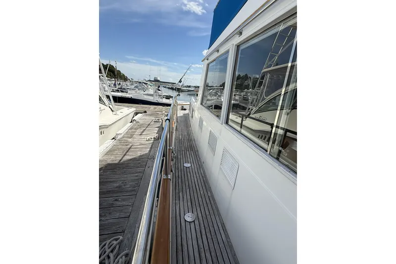 Slide: The Image of 1999 Grand Banks 42 Classic yacht docked at marina, showcasing side deck and windows. - 14