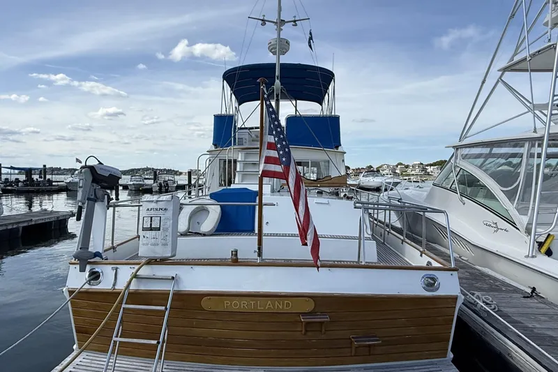 Slide: The Image of 1999 Grand Banks 42 Classic yacht docked in marina, featuring blue canopy and American flag. - 2
