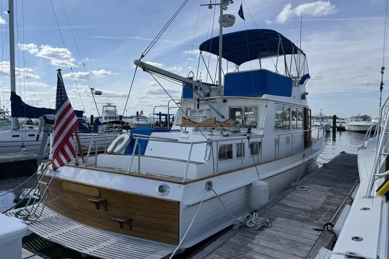 Slide: The Image of 1999 Grand Banks 42 Classic yacht docked, displaying American flag, with clear sky background. - 3