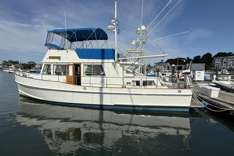 Slide: The Image of 1999 Grand Banks 42 Classic yacht docked at marina, featuring American flag and blue canopy. - 5