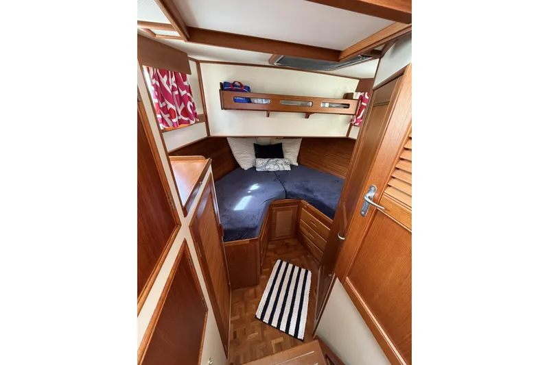 Slide: The Image of 1999 Grand Banks 42 Classic cabin interior with wood finish and cozy bedding. - 54