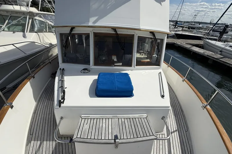 Slide: The Image of 1999 Grand Banks 42 Classic yacht docked at marina, featuring wooden deck and blue cover. - 9