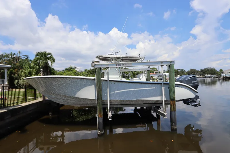 The Image of 2013 Yellowfin 32 Offshore boat on lift, docked by a scenic waterfront. - 0