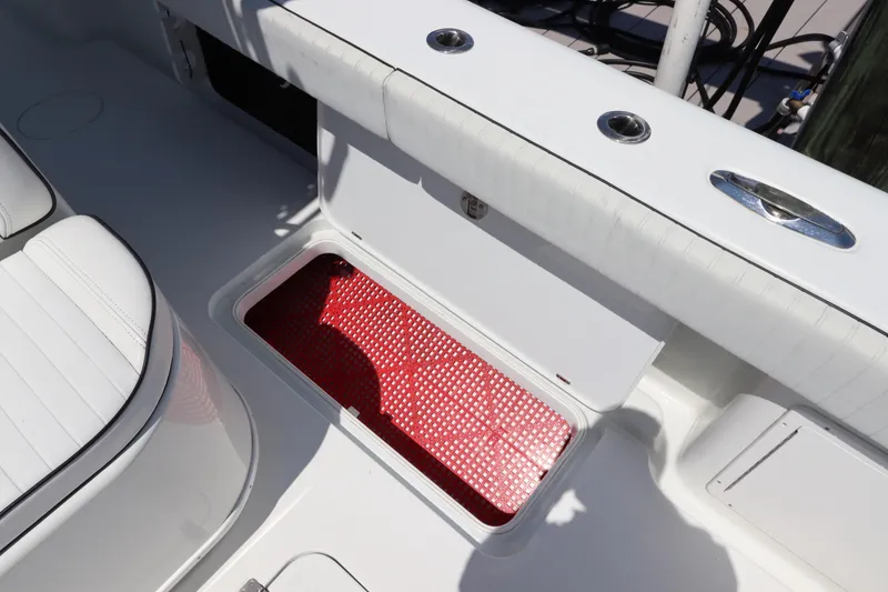 Slide: The Image of 2013 Yellowfin 32 Offshore boat with open storage compartment and red mat. - 18