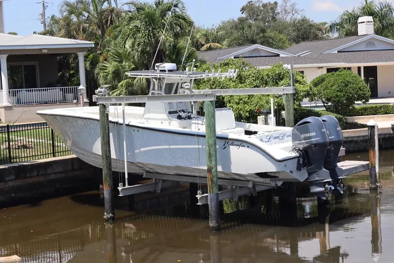 Slide: The Image of 2013 Yellowfin 32 Offshore boat on lift, docked near waterfront home. - 2