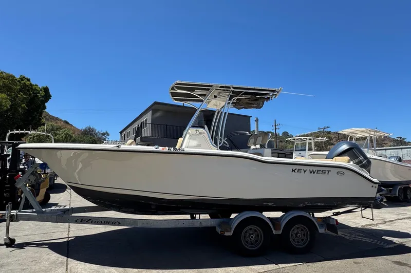 Slide: The Image of 2019 Key West 239 FS boat on trailer, parked outdoors under clear blue sky. - 12