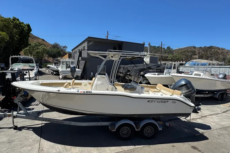 Slide: The Image of 2019 Key West 239 FS boat on trailer, parked outdoors under clear blue sky. - 13