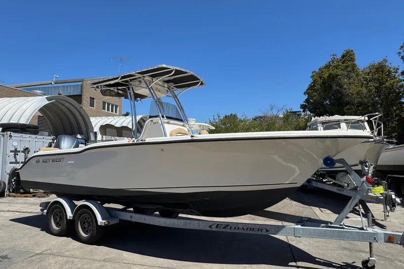 Slide: The Image of 2019 Key West 239 FS boat on trailer, parked outdoors under clear blue sky. - 2