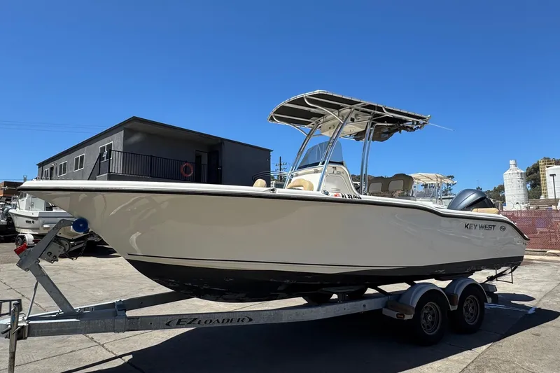 Slide: The Image of 2019 Key West 239 FS boat on trailer, parked outdoors under clear blue sky. - 5