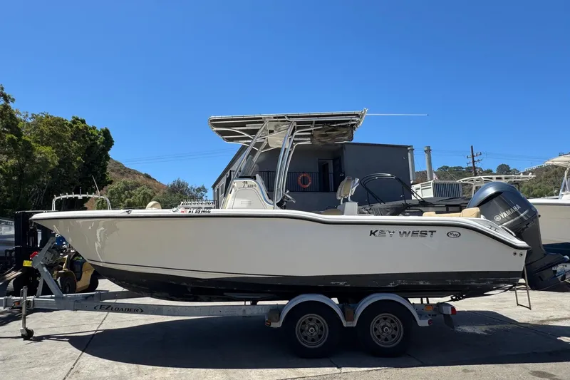 Slide: The Image of 2019 Key West 239 FS boat on trailer, parked outdoors under clear blue sky. - 7