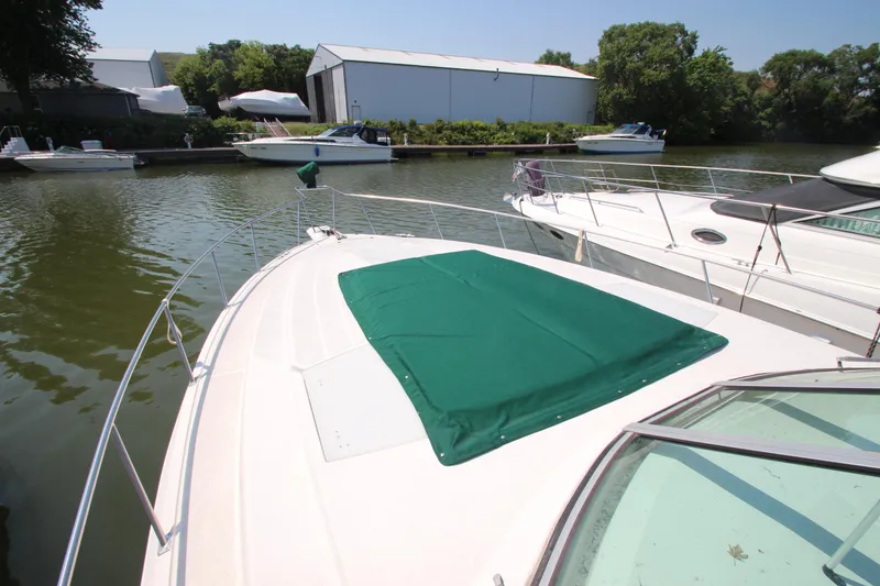 Slide: The Image of 1994 Cruisers Yachts Esprit 3775 docked, featuring green deck cover, surrounded by calm water. - 6
