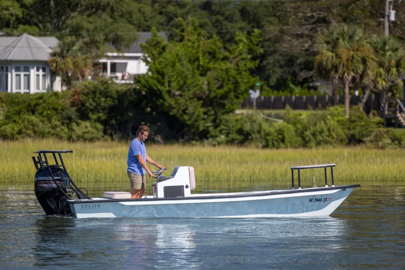 Slide: The Image of Man operating 2018 Xplor X18 boat on calm water near lush greenery. - 6
