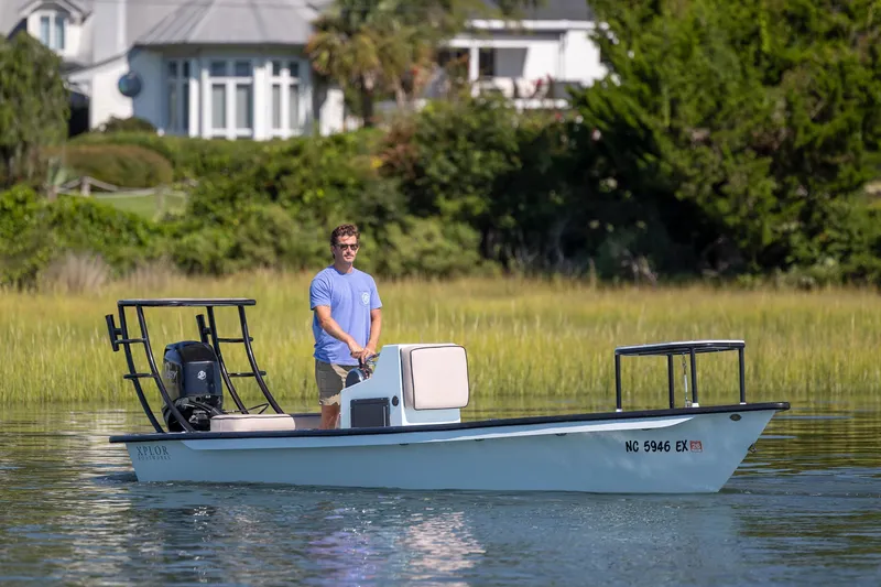 Slide: The Image of Man piloting 2018 Xplor X18 boat on calm water near lush greenery. - 7