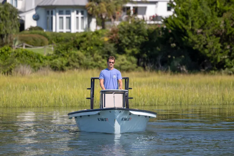 Slide: The Image of Man piloting 2018 Xplor X18 boat on calm water near lush greenery. - 8