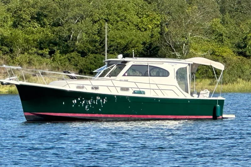 Slide: The Image of 2004 Mainship Pilot 30 boat on a calm lake with lush green background. - 1