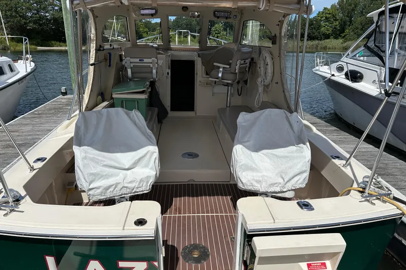 Slide: The Image of 2004 Mainship Pilot 30 boat interior with covered seats, docked at a marina. - 11