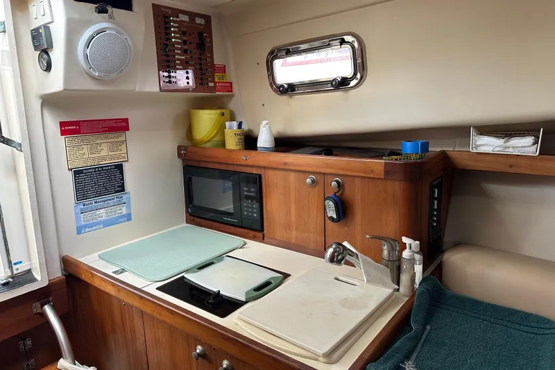 Slide: The Image of 2004 Mainship Pilot 30 boat interior with kitchenette, microwave, sink, and control panel. - 14