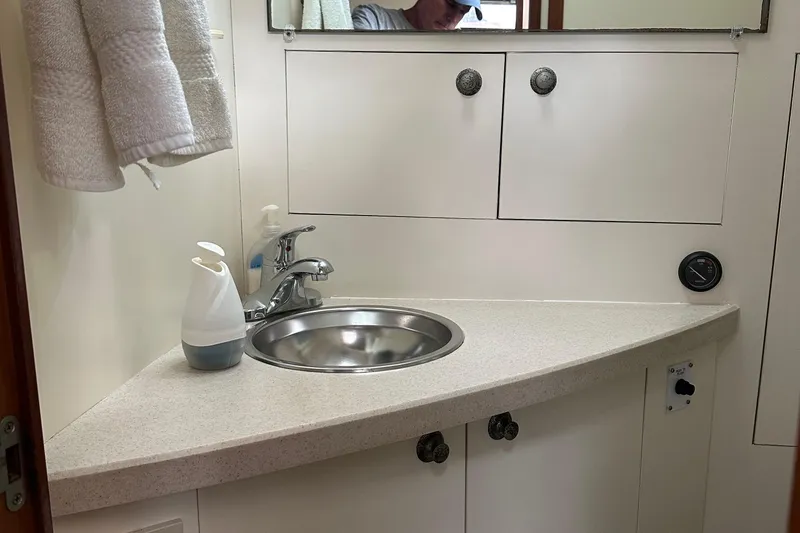 Slide: The Image of 2004 Mainship Pilot 30 bathroom with sink, mirror, and storage cabinets. - 16