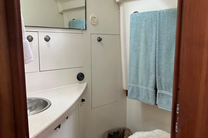Slide: The Image of 2004 Mainship Pilot 30 bathroom with sink, cabinets, and blue towels. - 17
