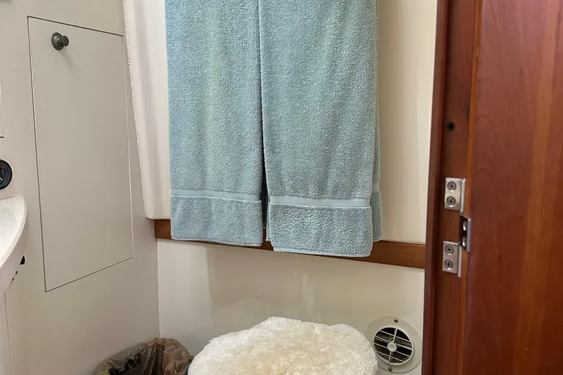 Slide: The Image of Bathroom interior of 2004 Mainship Pilot 30 with blue towel and wooden door. - 18