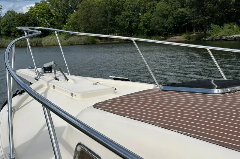 Slide: The Image of 2004 Mainship Pilot 30 boat deck with railing, on a serene lake background. - 4
