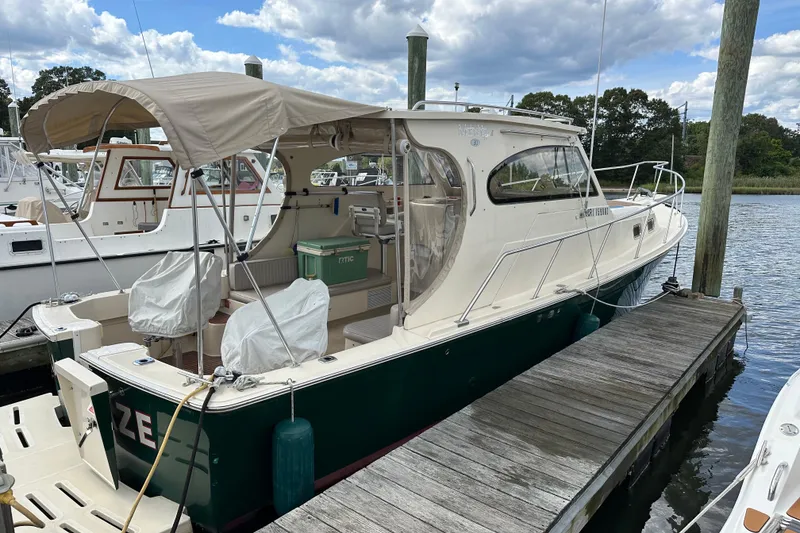 Slide: The Image of 2004 Mainship Pilot 30 docked, featuring a beige canopy and green hull. - 6
