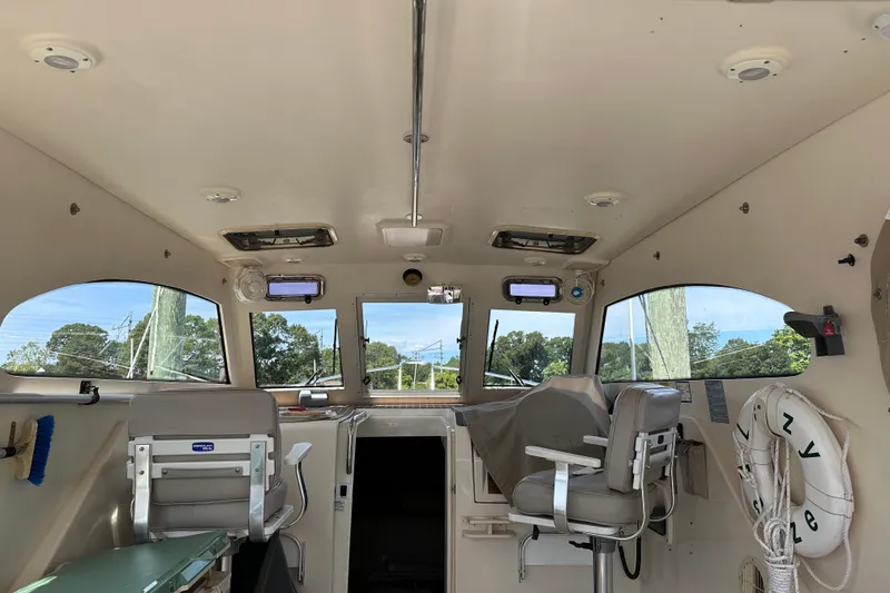 Slide: The Image of Interior of a 2004 Mainship Pilot 30 boat, featuring seating and windows. - 8