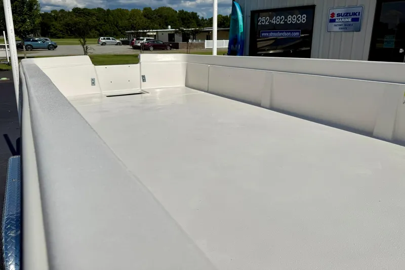 Slide: The Image of 2026 Carolina Skiff E24 DLX Kit Boat, spacious deck, parked outdoors near marine service. - 12