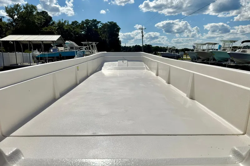 Slide: The Image of 2026 Carolina Skiff E24 DLX Kit Boat, spacious deck under a clear blue sky. - 14