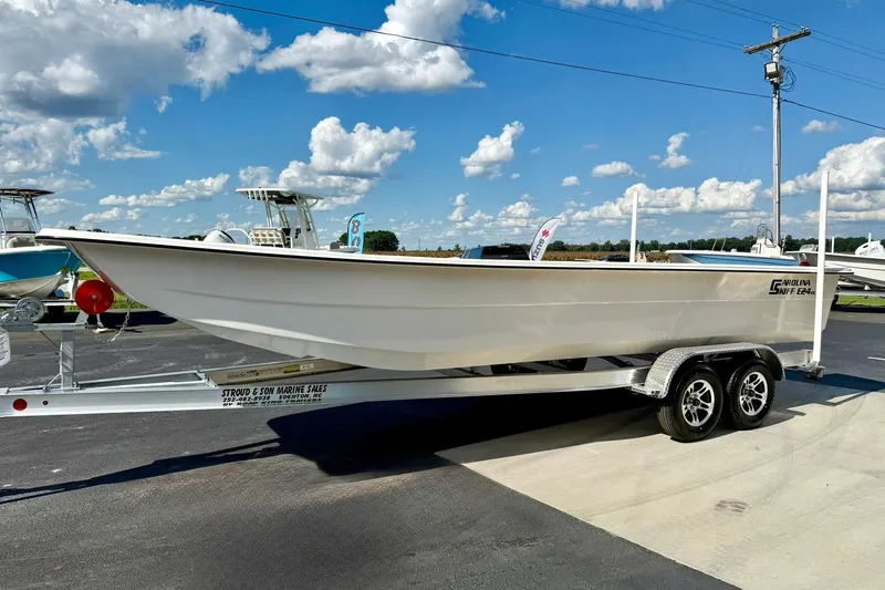 Slide: The Image of 2026 Carolina Skiff E24 DLX Kit Boat on trailer under blue sky. - 4
