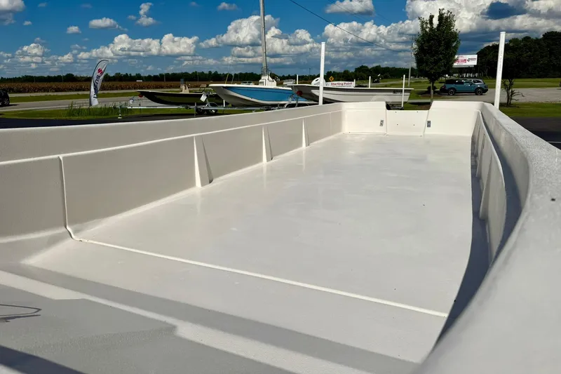 Slide: The Image of 2026 Carolina Skiff E24 DLX Kit Boat, spacious interior, parked outdoors under a blue sky. - 8