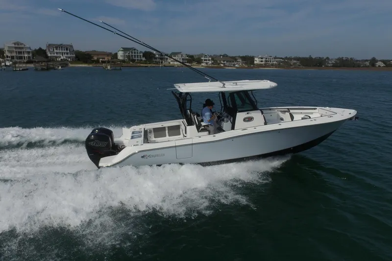 Slide: The Image of 2023 Crevalle 33 CSF boat cruising on water near coastal homes. - 7