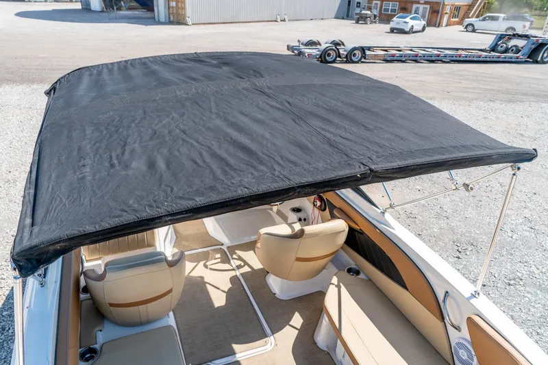 Slide: The Image of 2018 Sea Ray SPX 210 boat with black canopy and beige interior seating. - 25