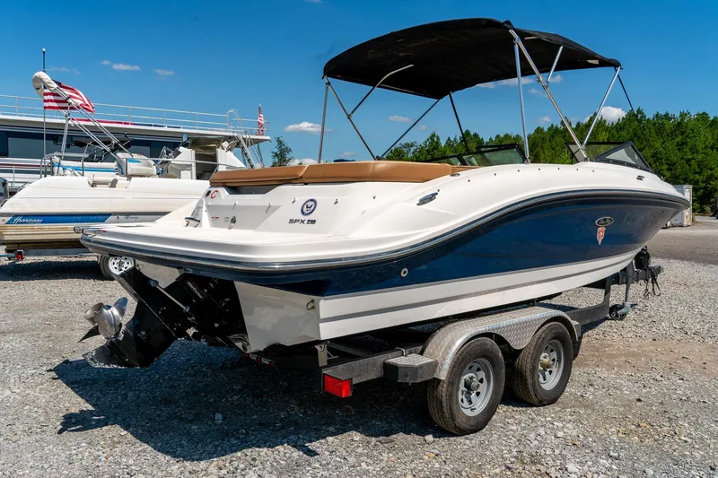Slide: The Image of 2018 Sea Ray SPX 210 boat on trailer, parked outdoors under clear blue sky. - 4
