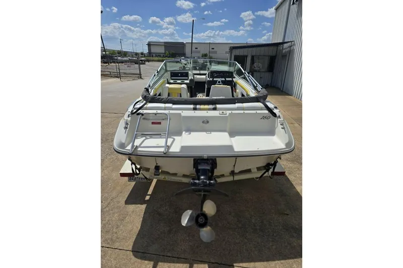 Slide: The Image of 1990 Sea Ray 160 Bow Rider boat, rear view, parked outdoors under a sunny sky. - 3
