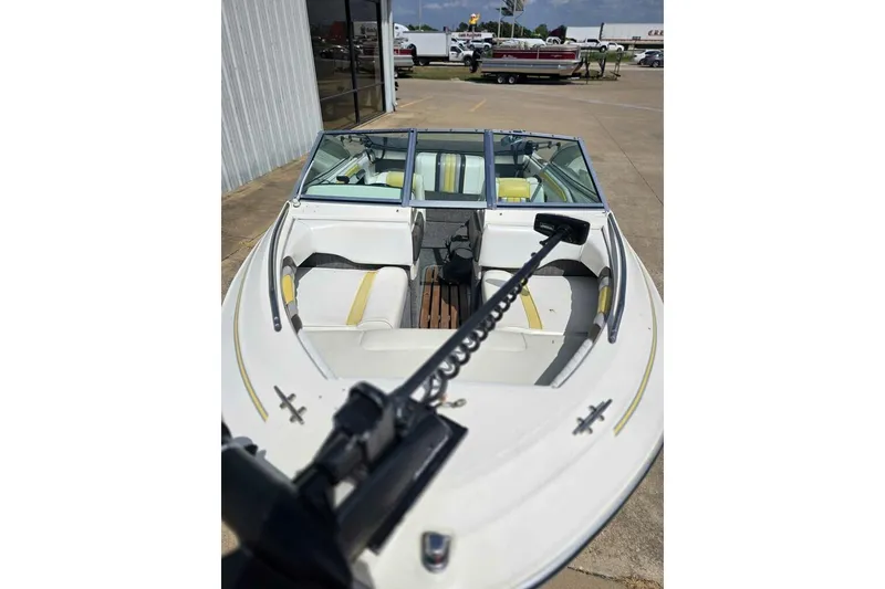 Slide: The Image of 1990 Sea Ray 160 Bow Rider boat with yellow accents, parked outdoors. - 4