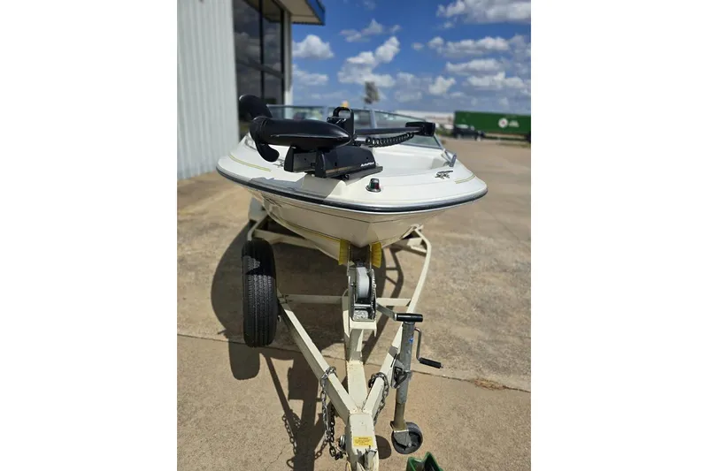 Slide: The Image of 1990 Sea Ray 160 Bow Rider on trailer, parked outdoors under a clear blue sky. - 5