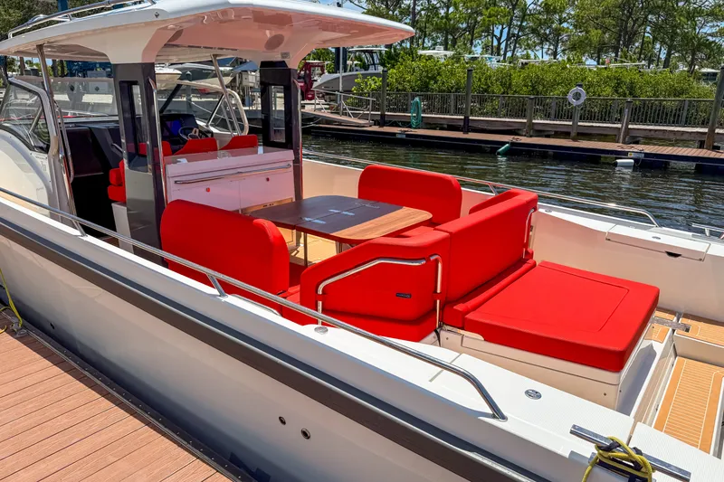 Slide: The Image of 2025 Nimbus Tender 11 boat with vibrant red seating, docked at a marina. - 2