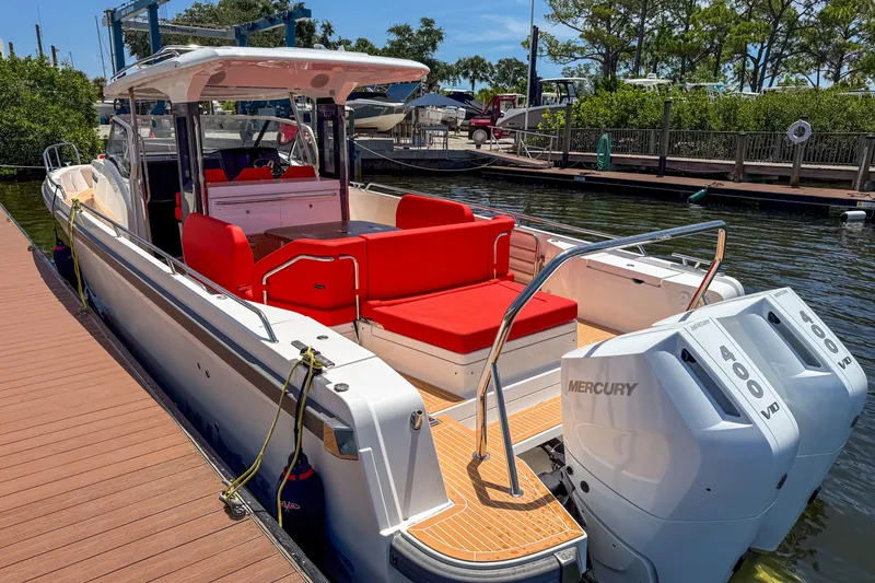 Slide: The Image of 2025 Nimbus Tender 11 boat with red seating and dual Mercury 400 engines docked. - 3