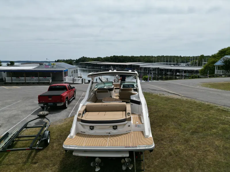 Slide: The Image of 2022 Sea Ray SLX 310 boat on trailer near marina, with red truck nearby. - 12