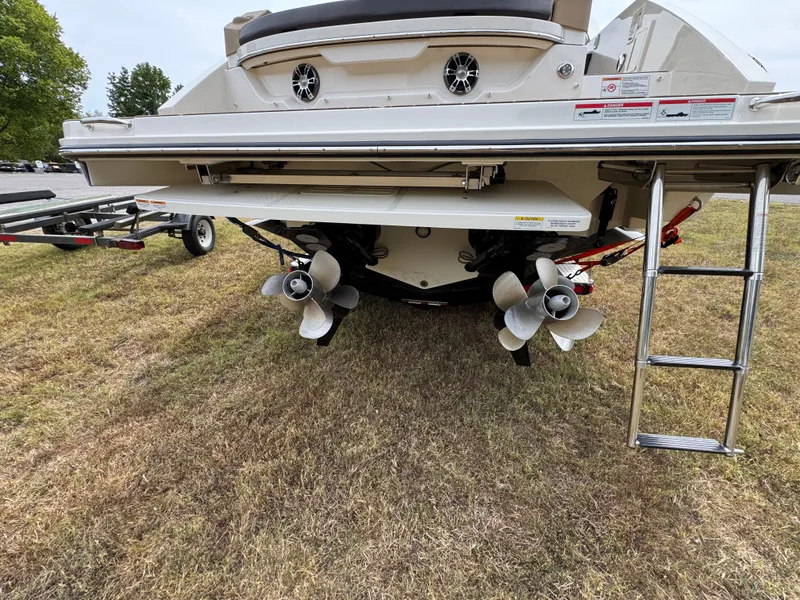 Slide: The Image of 2022 Sea Ray SLX 310 boat rear view with dual propellers and ladder on grass. - 19