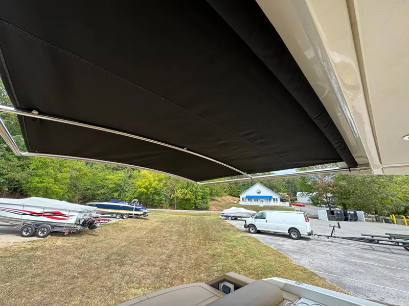 Slide: The Image of 2022 Sea Ray SLX 310 boat with extended canopy, parked near trailers and vehicles. - 26