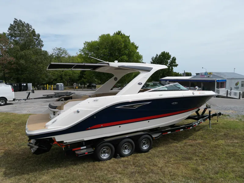 Slide: The Image of 2022 Sea Ray SLX 310 boat on trailer, parked on grass near trees and buildings. - 3