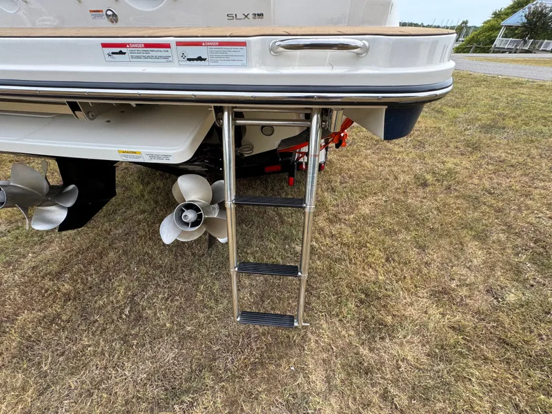 Slide: The Image of 2022 Sea Ray SLX 310 boat with ladder and propellers on grassy area. - 32