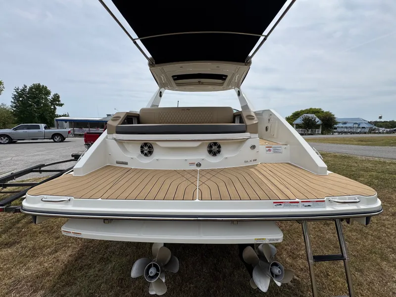 Slide: The Image of 2022 Sea Ray SLX 310 boat with spacious deck and seating, parked on grass. - 33