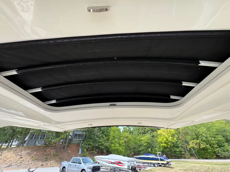 Slide: The Image of 2022 Sea Ray SLX 310 boat with retractable sunroof, parked near trees and vehicles. - 37