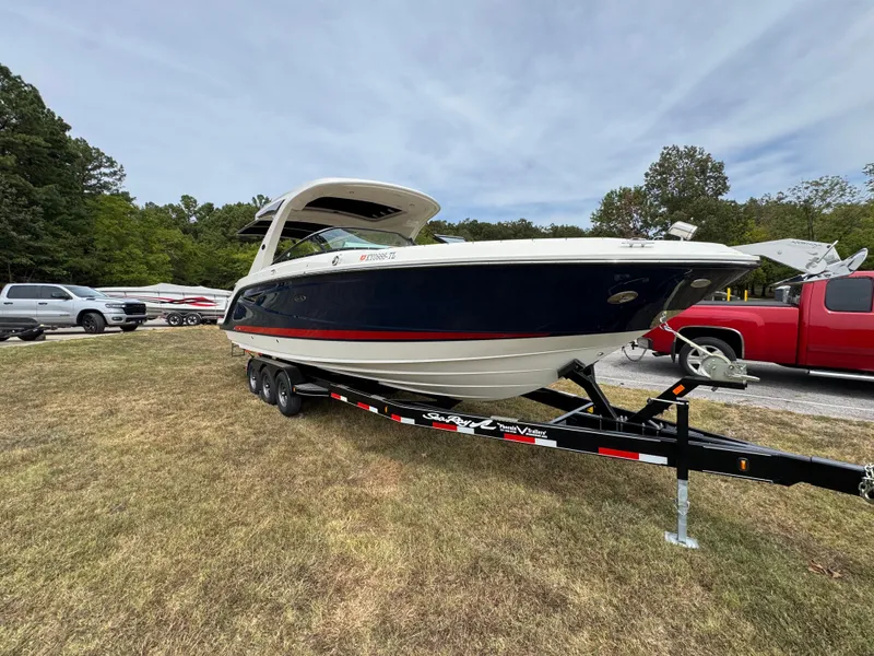 Slide: The Image of 2022 Sea Ray SLX 310 boat on trailer, parked on grass with trees in background. - 8